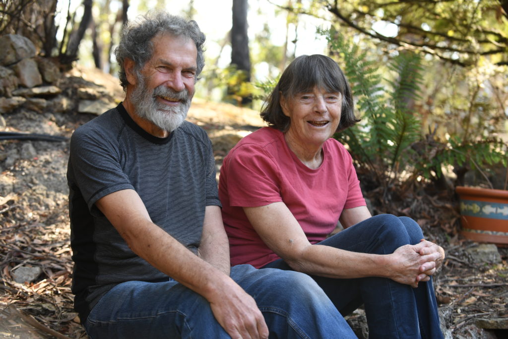An older man and woman sitting on stone steps smiling.